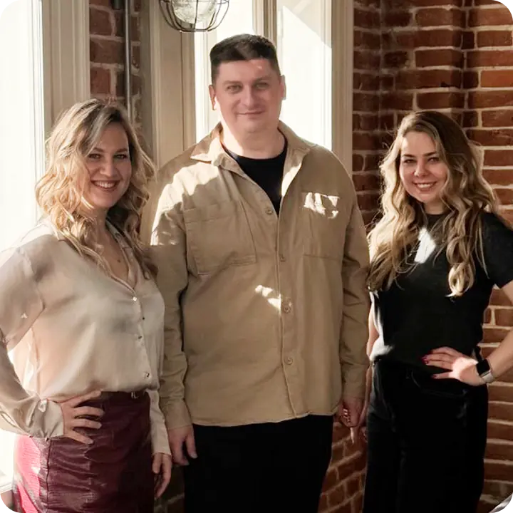 Three people posing indoors, smiling.