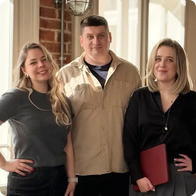 Three people posing indoors, smiling.